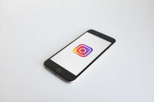 foto de celular em cima de uma mesa mostrando o logo do instagram em sua tela